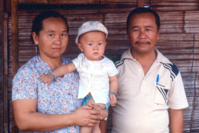 A mother and father holding their baby between them